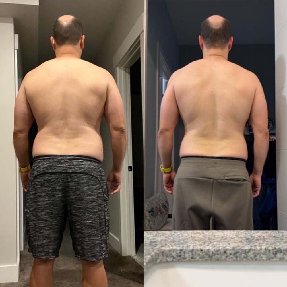 A man without a shirt is standing in front of a mirror.