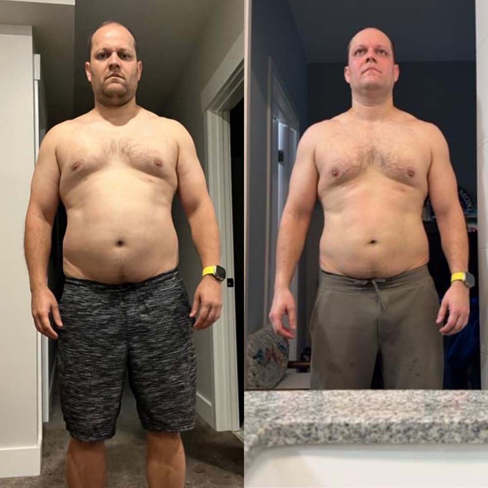 A man without a shirt is standing in front of a mirror.