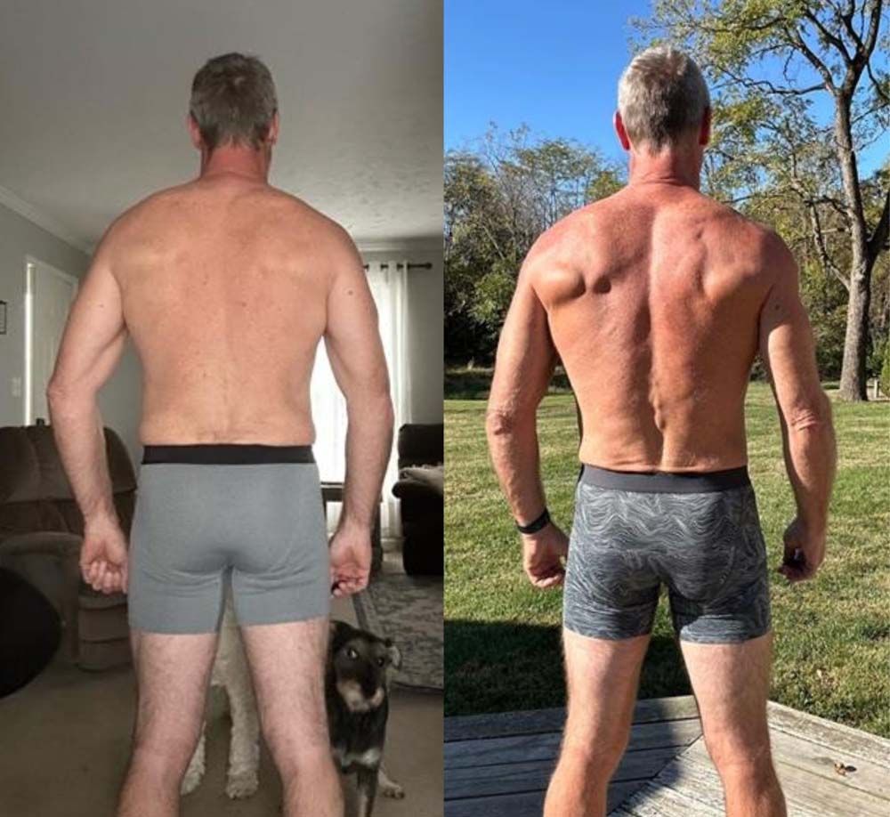 A man without a shirt is standing next to a dog