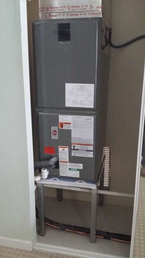 An air conditioner is sitting on top of a shelf in a room.