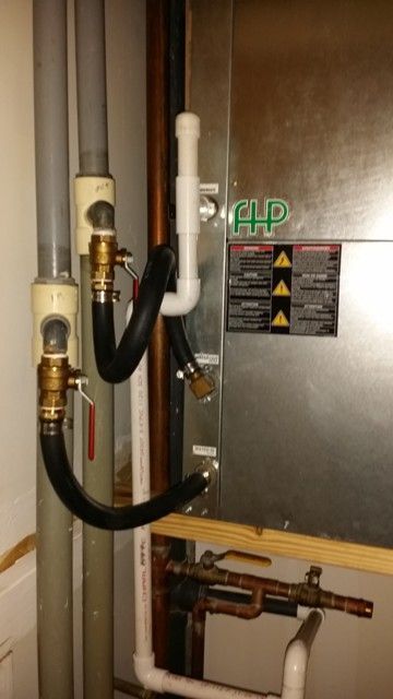 A hose is attached to a wall next to a heater.