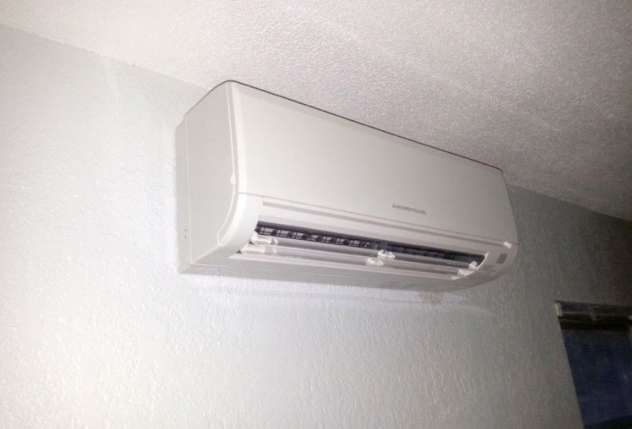 A white air conditioner is mounted on a white wall.