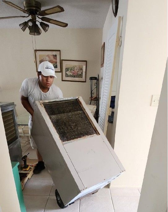 A man is pushing a refrigerator on a cart