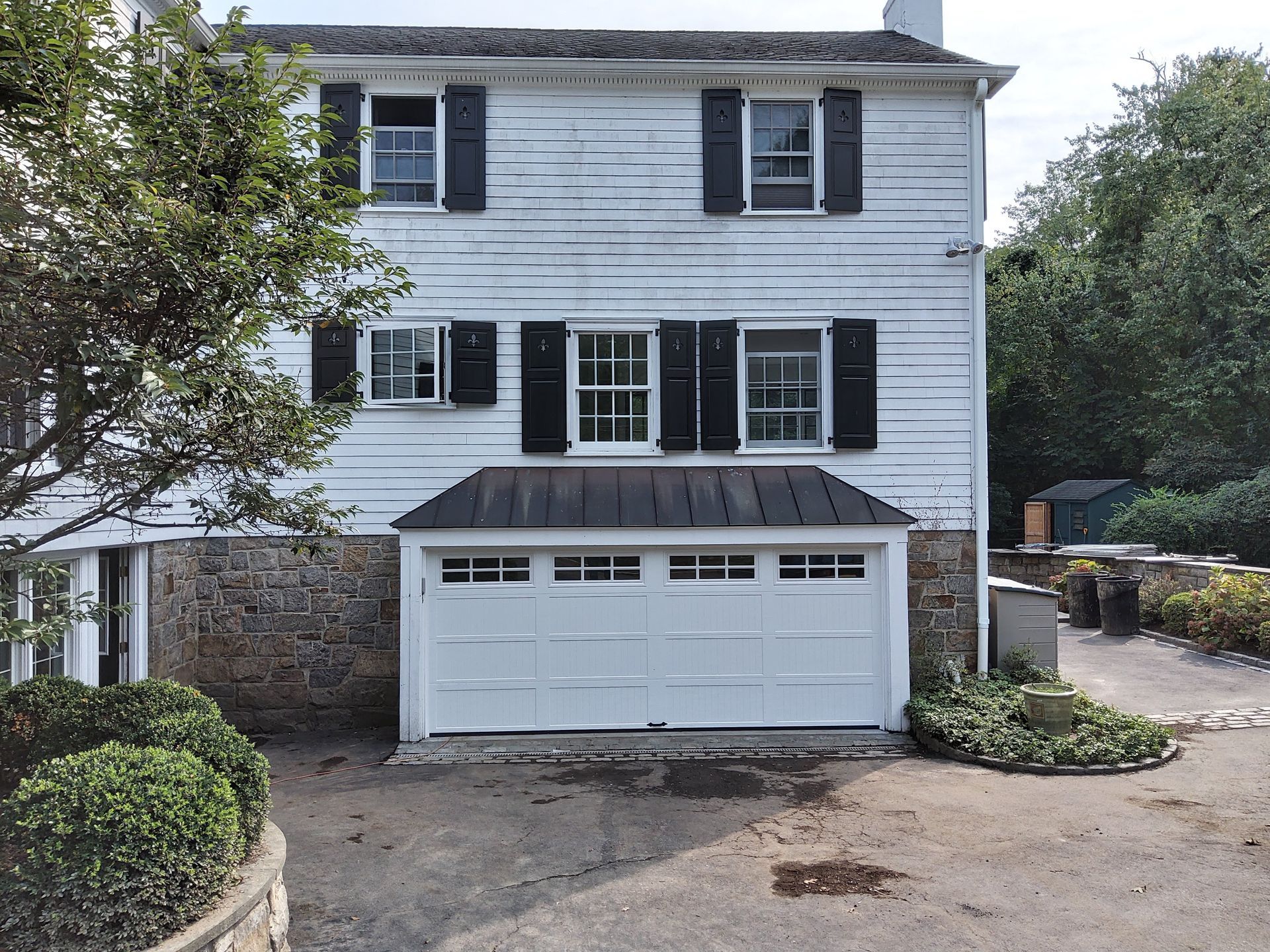Two-story white house with black shutters and double garage, viewed from the driveway