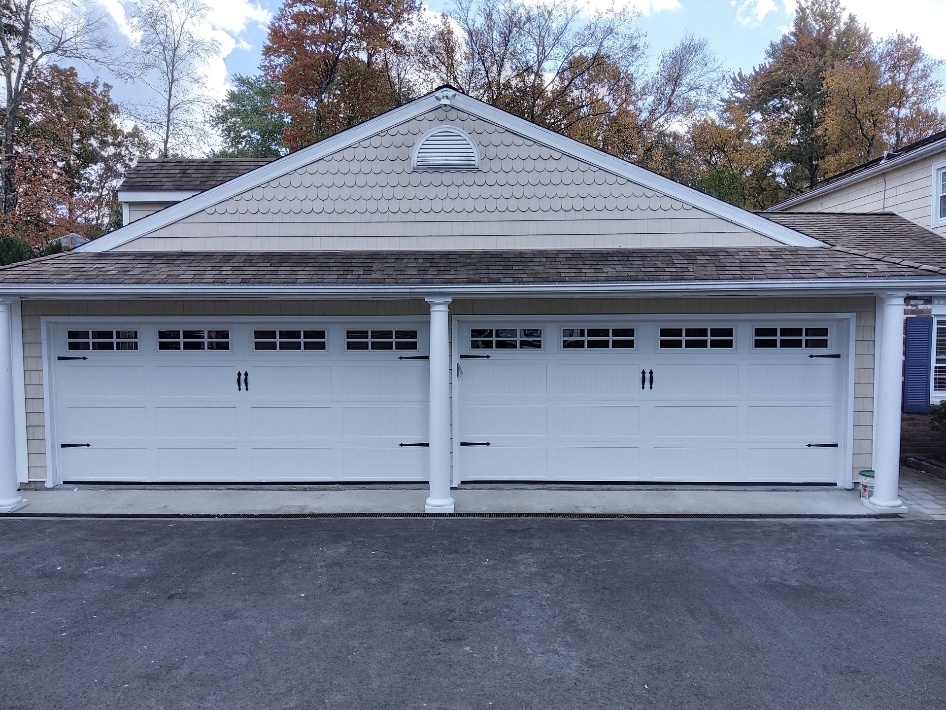 White double garage doors on a gray shingled two-car garage with a peaked roof.