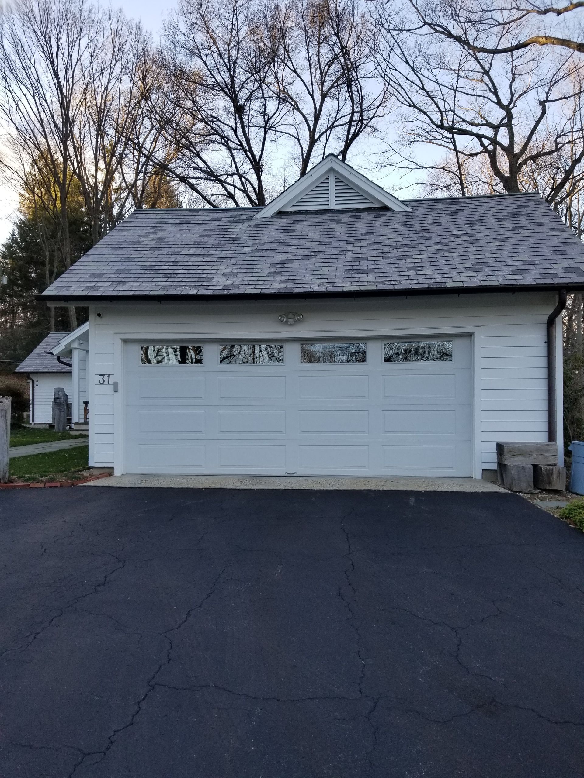 White double garage with gray shingle roof and asphalt driveway in a suburban setting