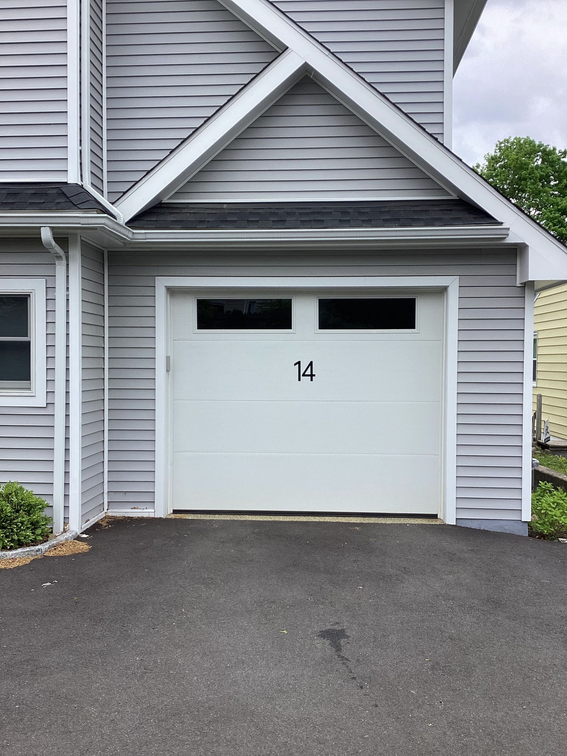 White garage door with number 14 on a gray house beside a driveway