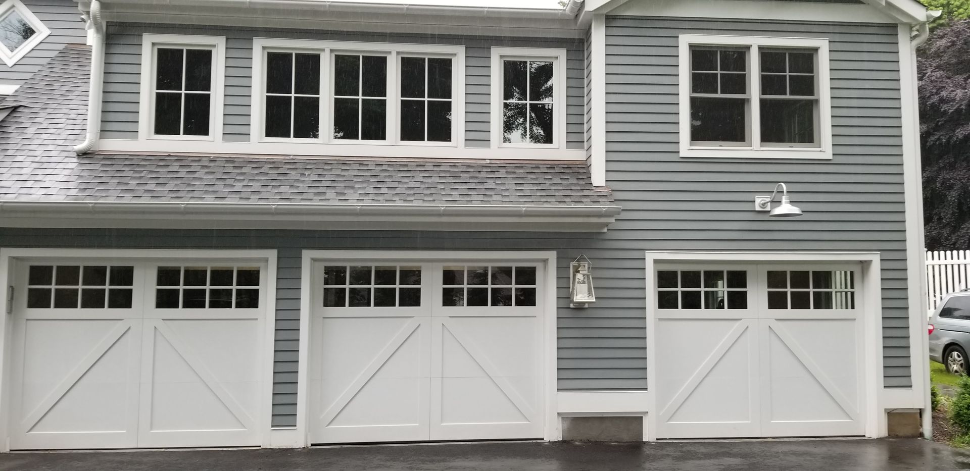 Gray house exterior with three white garage doors and upper windows