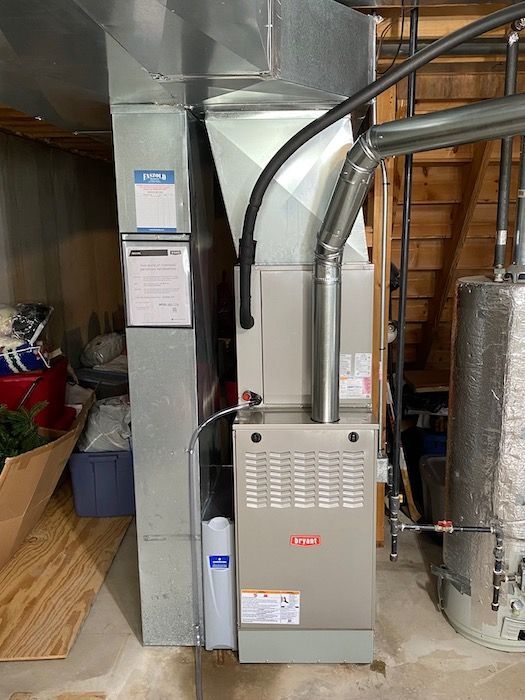 A water heater is sitting next to a bunch of pipes.