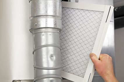 A person is holding a filter next to a metal pipe.