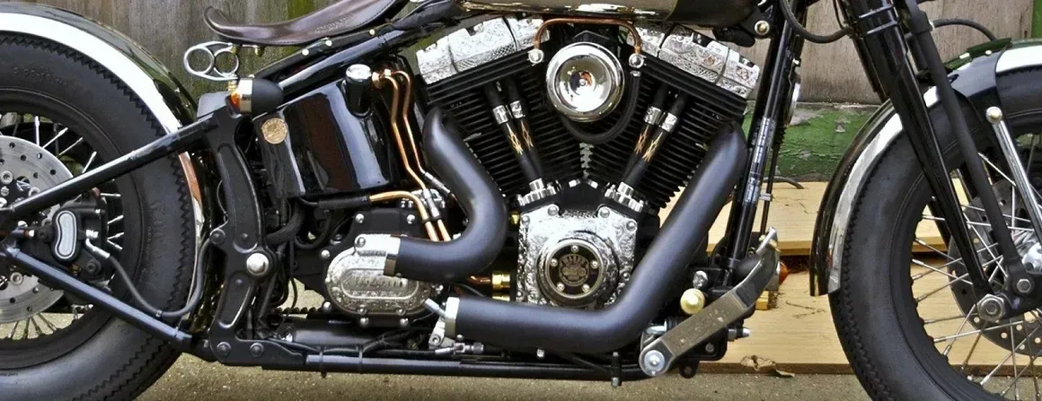 Black custom motorcycle, detailed engine, dark pipes, and chrome accents.