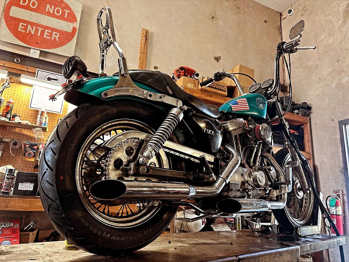 Turquoise Harley Davidson motorcycle inside a workshop with a