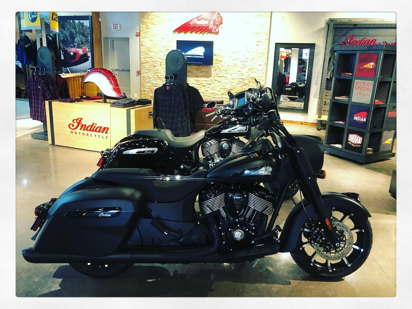 Black Indian motorcycle parked inside a showroom with clothing and merchandise.