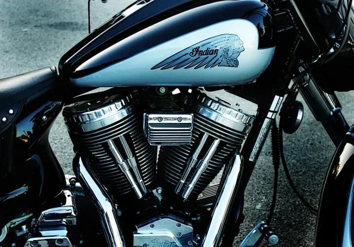 Close-up of an Indian motorcycle gas tank, black and silver, with the Indian logo, and engine.
