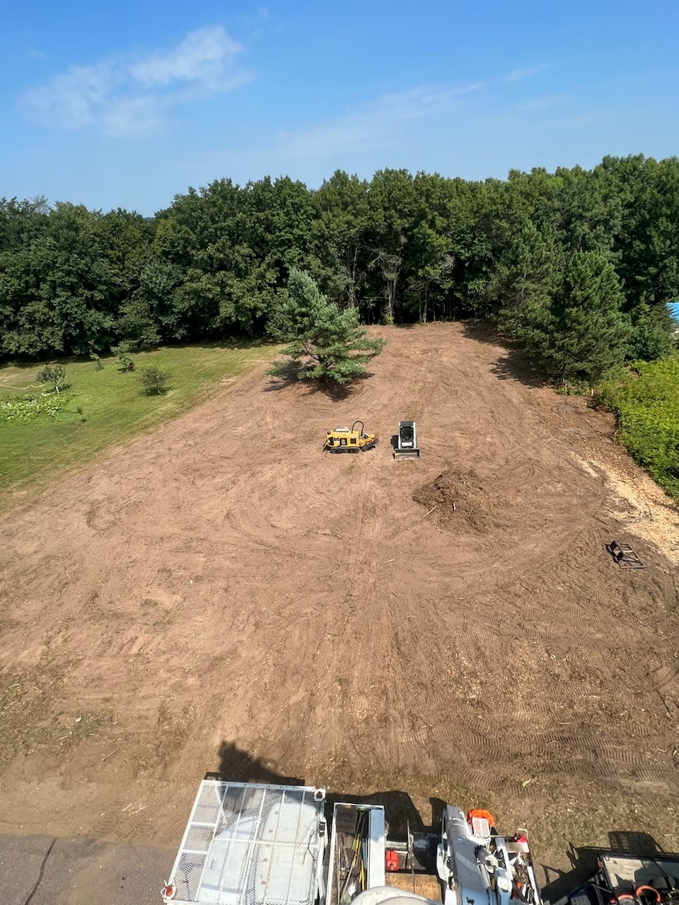 An aerial view of a dirt field with trees in the background.