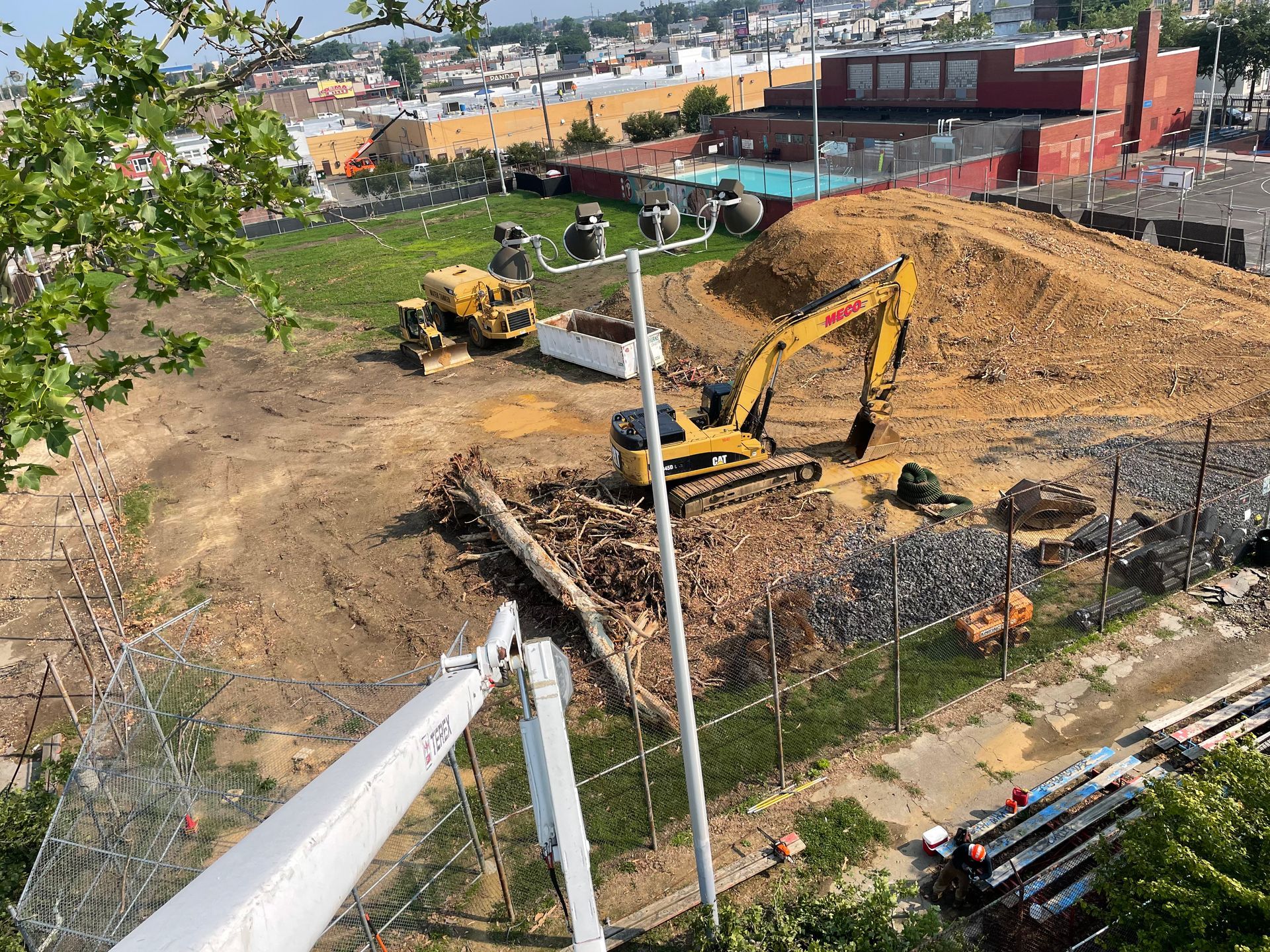 Construction site with excavators, a pile of dirt, and logs. Viewed from above.