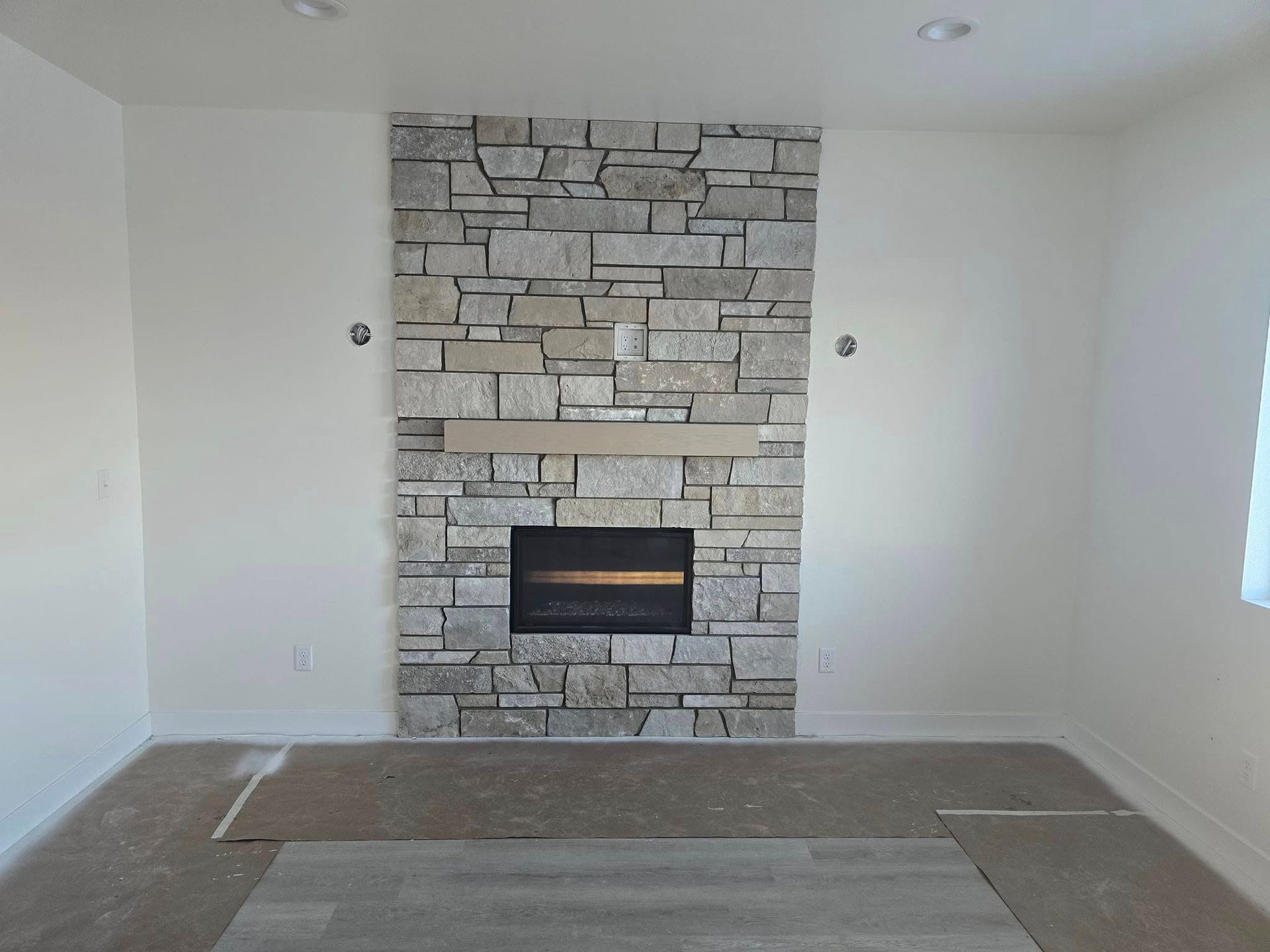 an empty room with a stone fireplace in the middle
