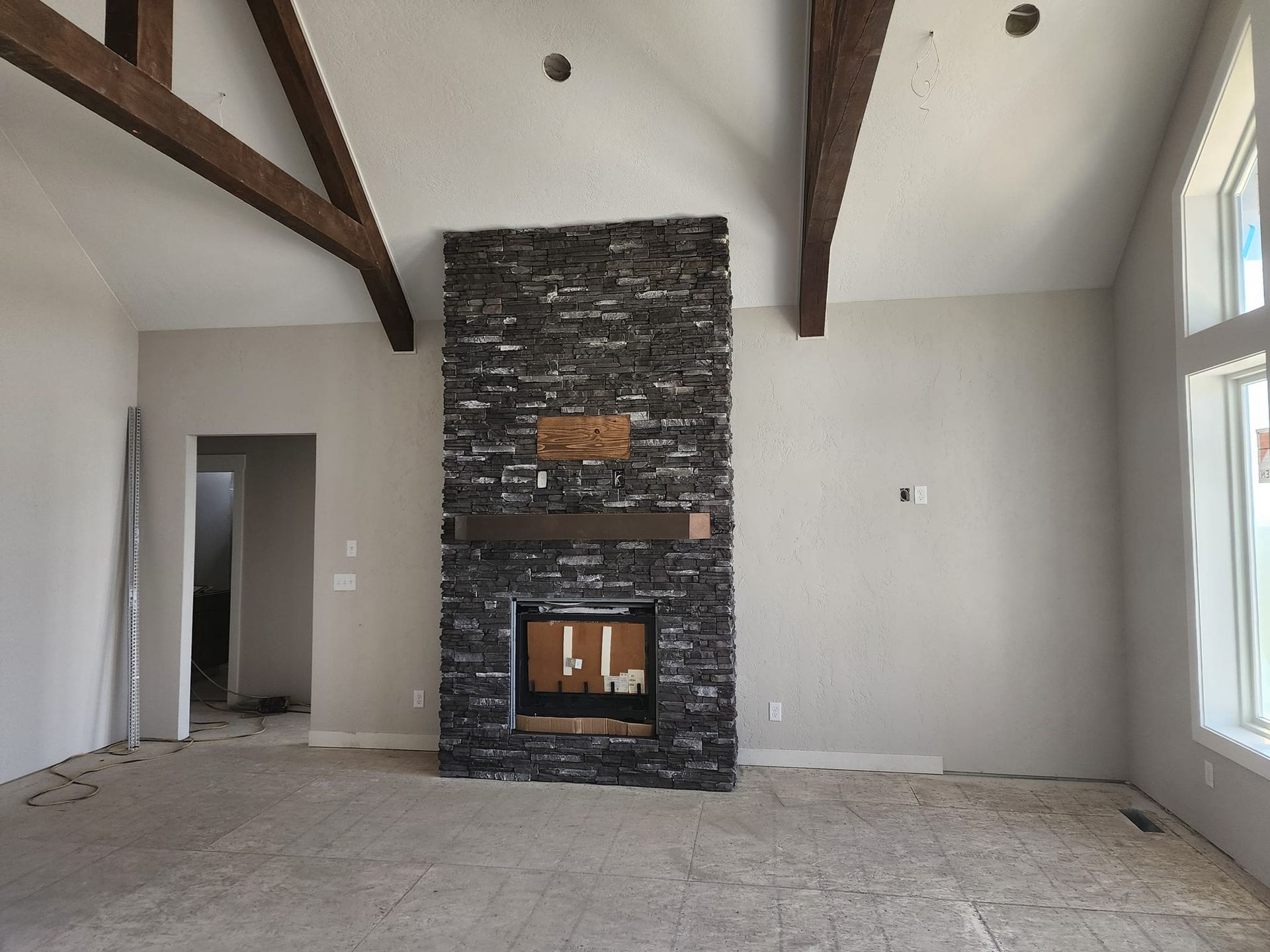 an empty living room with a large stone fireplace