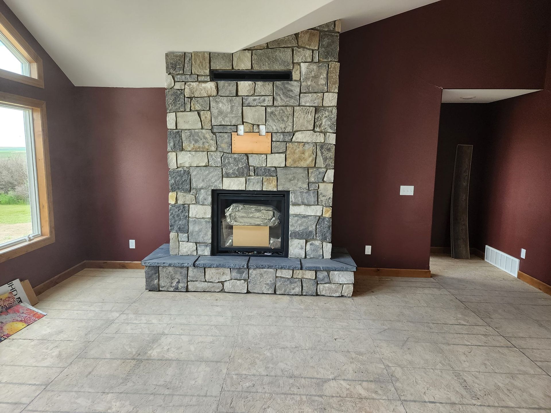 an empty room with a stone fireplace in the middle