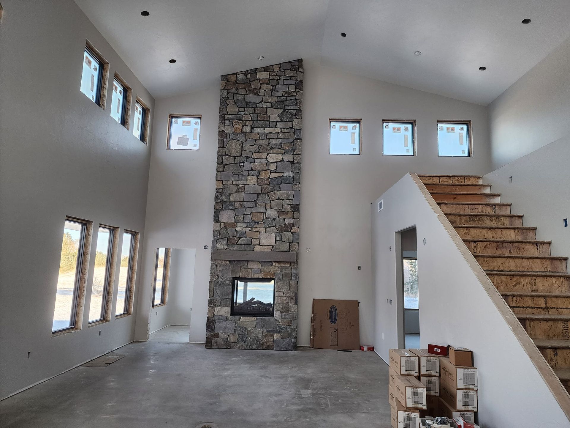 a large room with a stone fireplace and stairs
