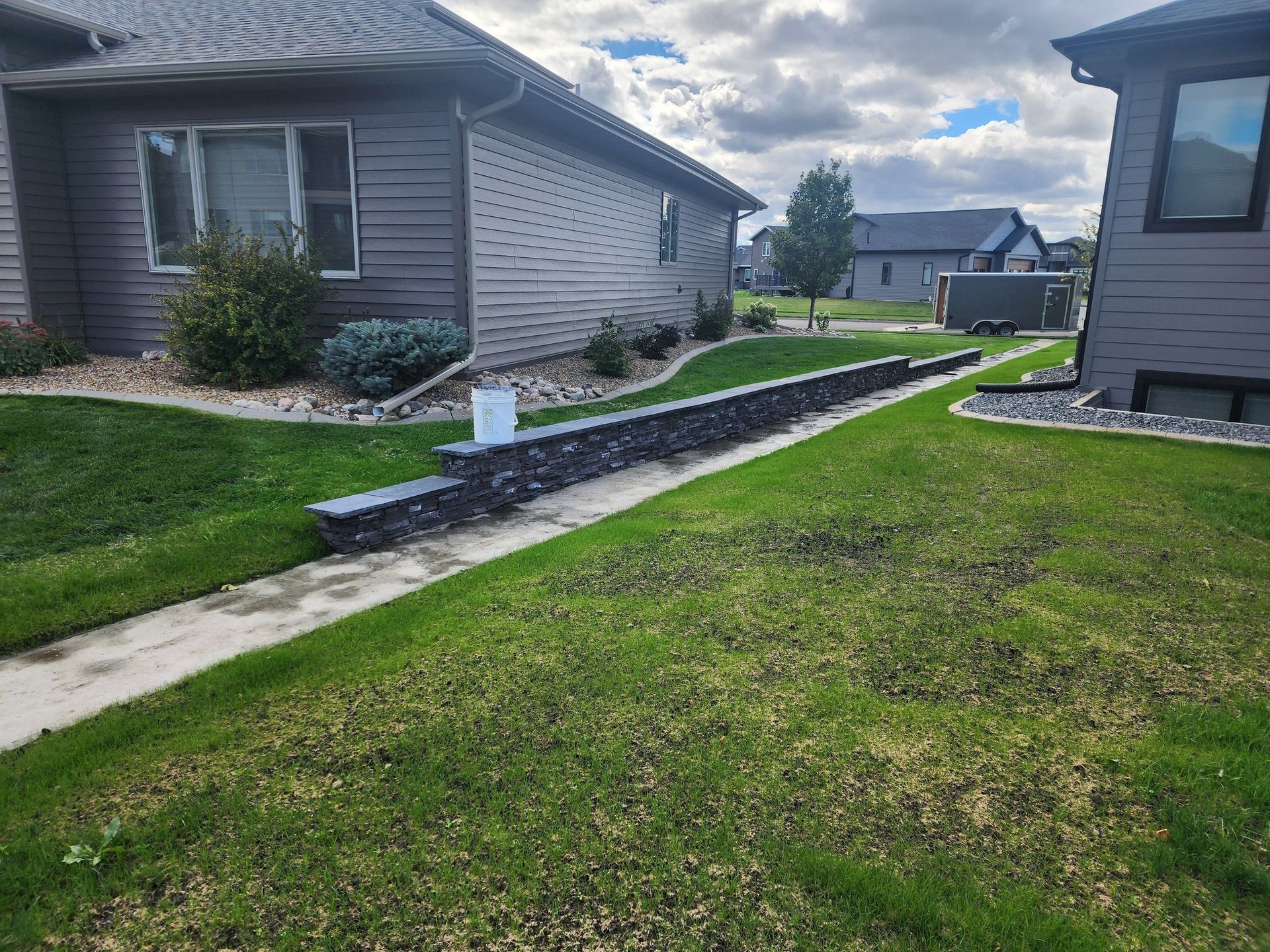 a house with a lush green lawn and a stone wall in front of it