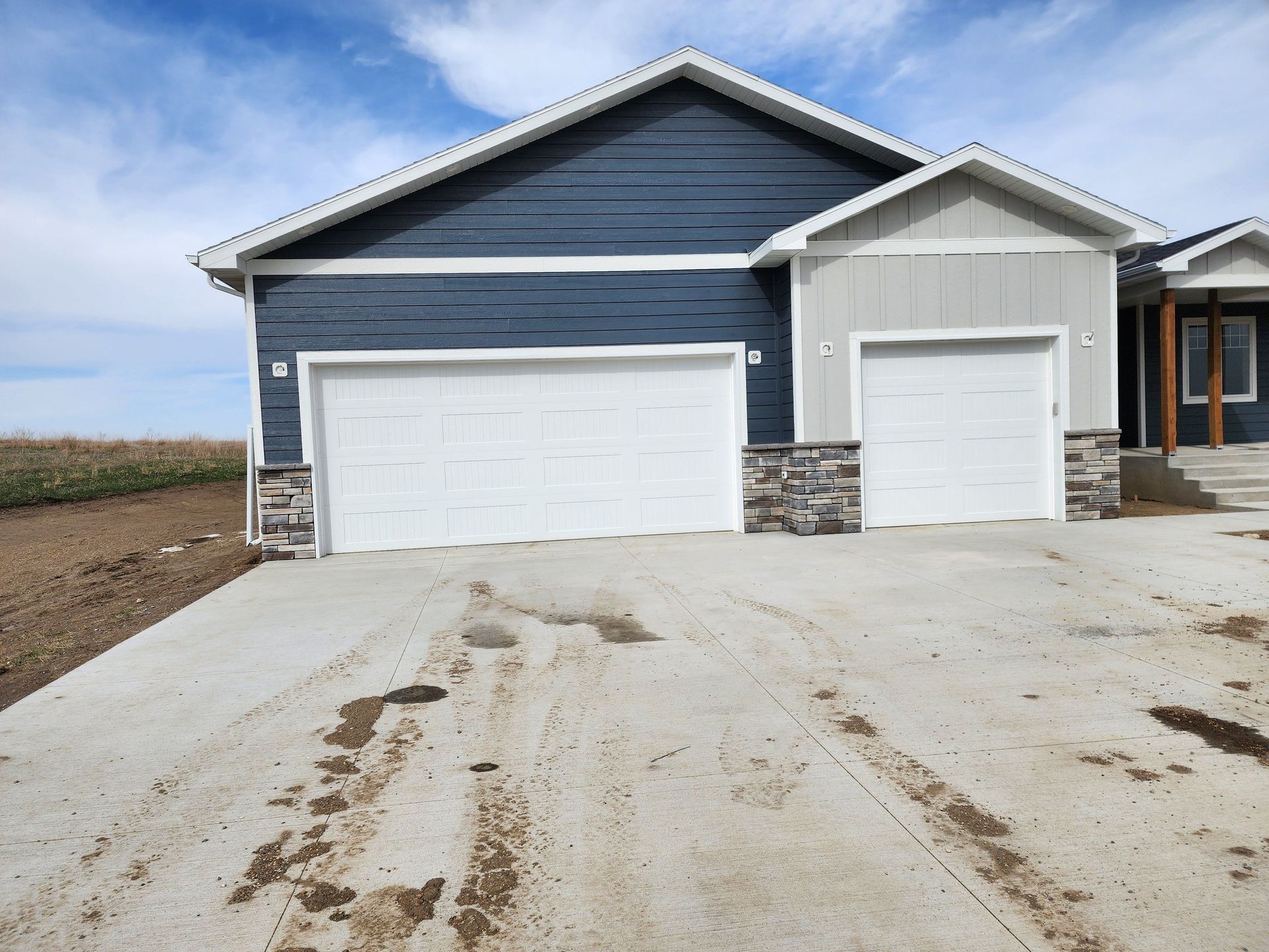 a house with two garage doors and a concrete driveway