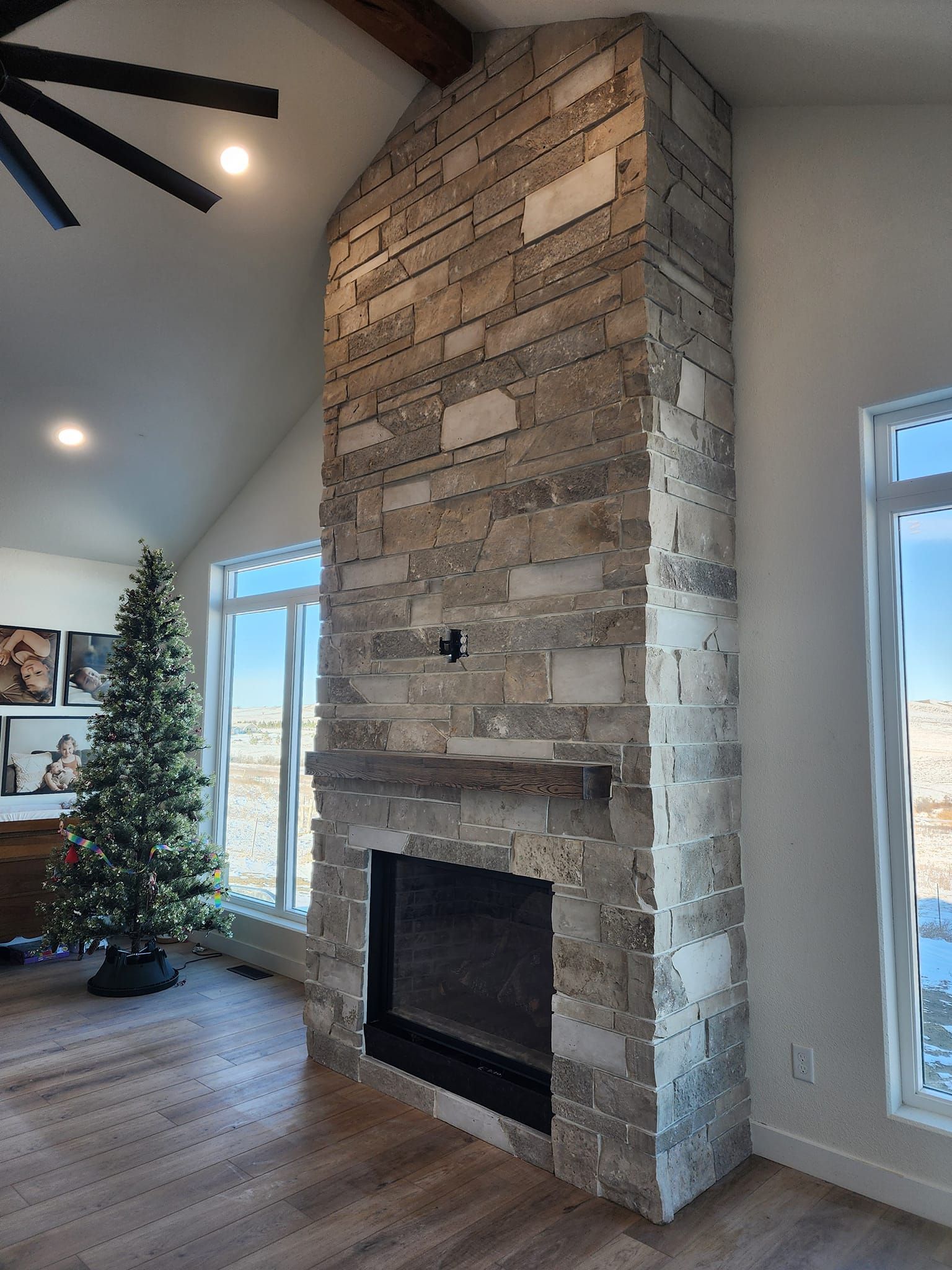 a living room with a fireplace and a Christmas tree and ceiling fan