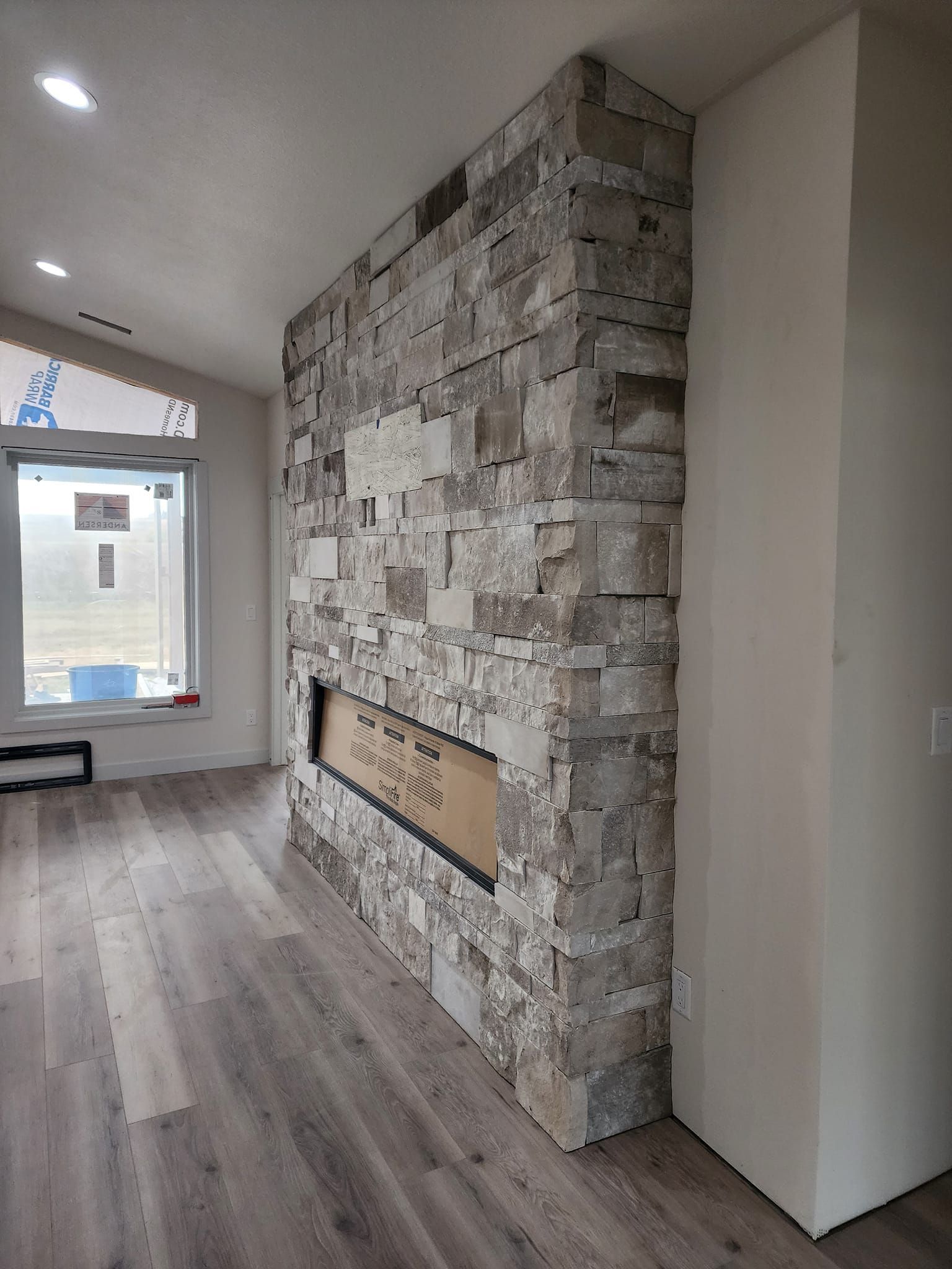 a living room with a stone fireplace and hardwood floors