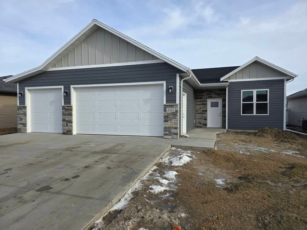 the front of a house with two garage doors and a driveway