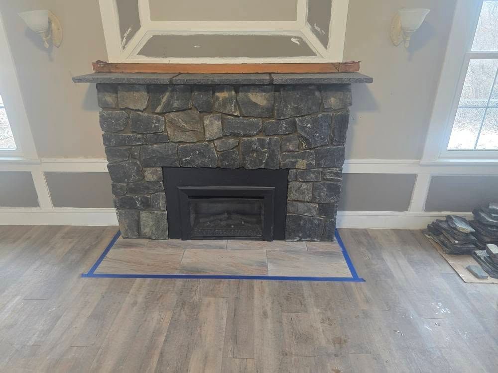 a living room with a stone fireplace and a wooden floor