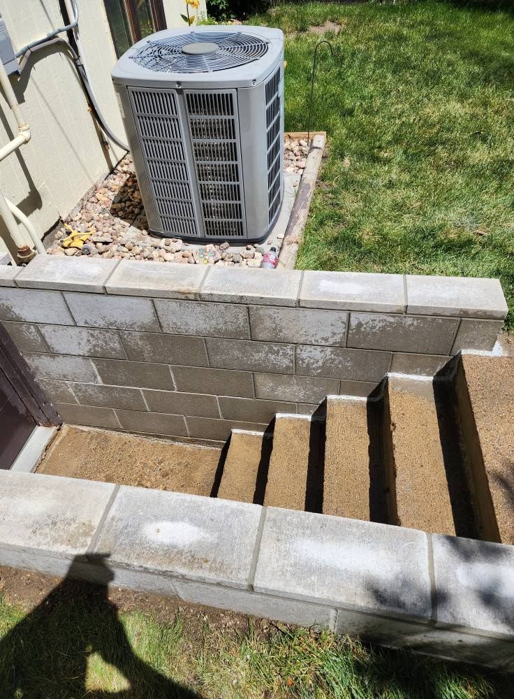 an air conditioner next to a brick wall and steps