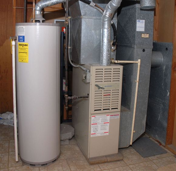 Basement utility room with water heater, furnace, and exposed ductwork.