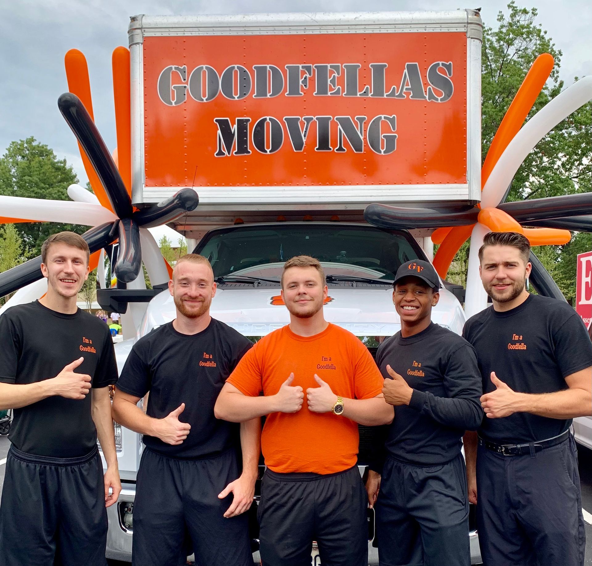 A group of men standing in front of a goodfellas moving truck