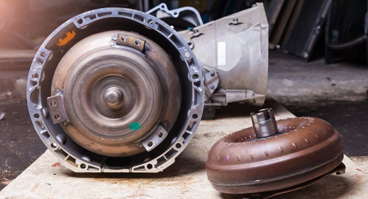 Car transmission components, including a torque converter, on a workbench in a repair shop.