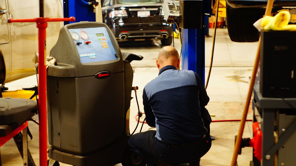 Mechanic working on car with a machine in a garage.