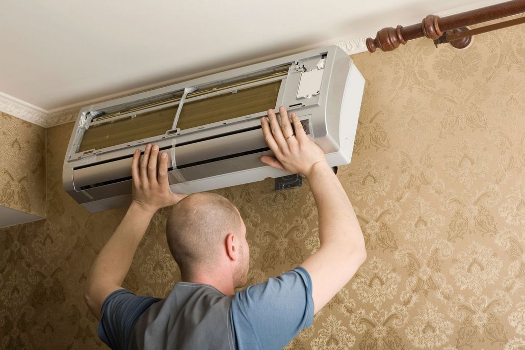 Technician installing a wall-mounted air conditioner indoors