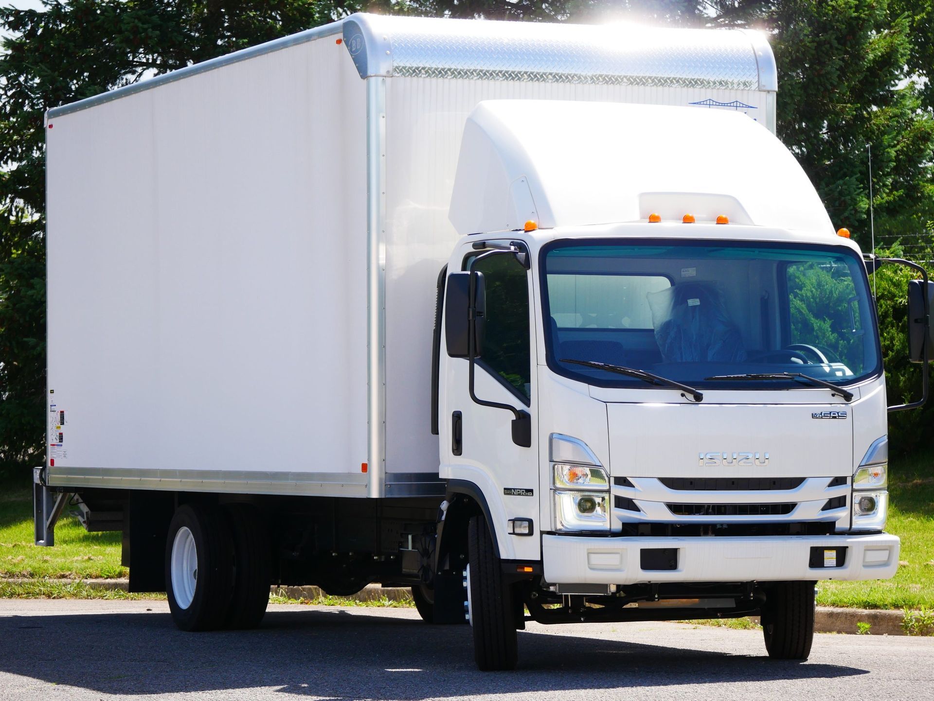 White box truck parked on a road. White body, black tires, and a driver's cabin.