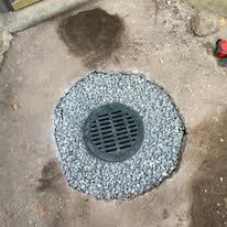 A manhole cover is sitting on top of a pile of gravel.