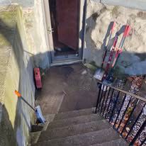 A set of stairs leading up to a doorway with a broom and shovel.