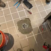 A manhole cover is being installed on a tiled floor.