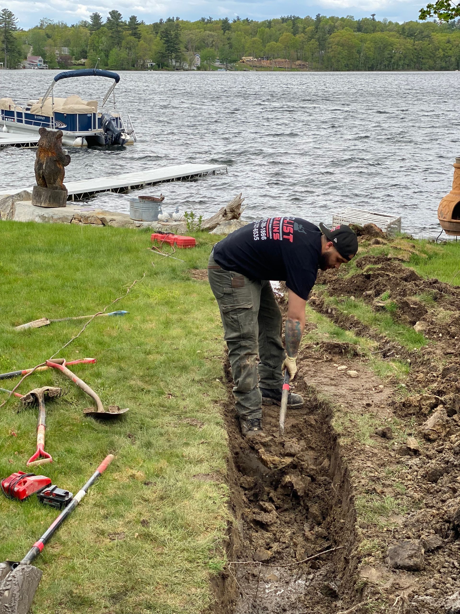 A man is digging in the dirt near a lake.