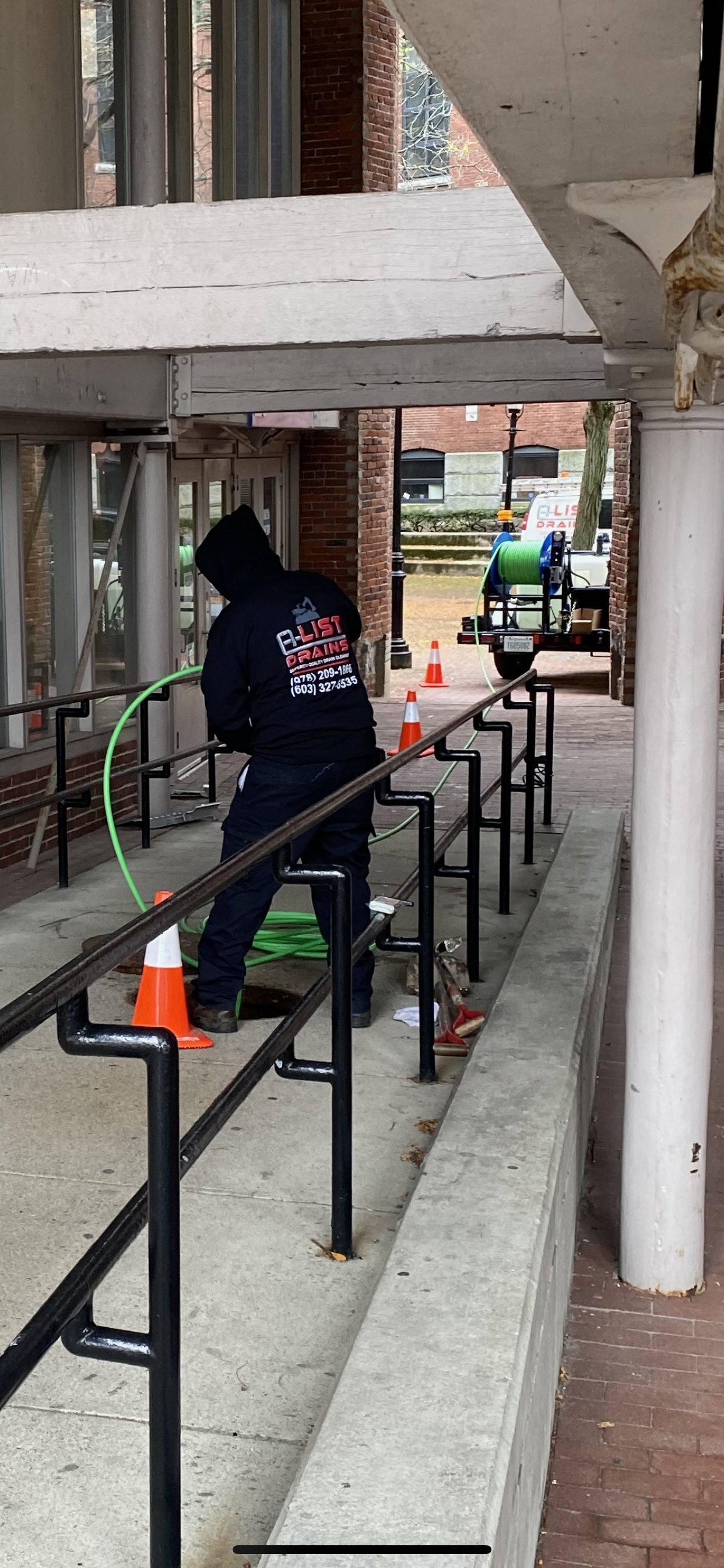 A man is standing on a railing holding a hose.