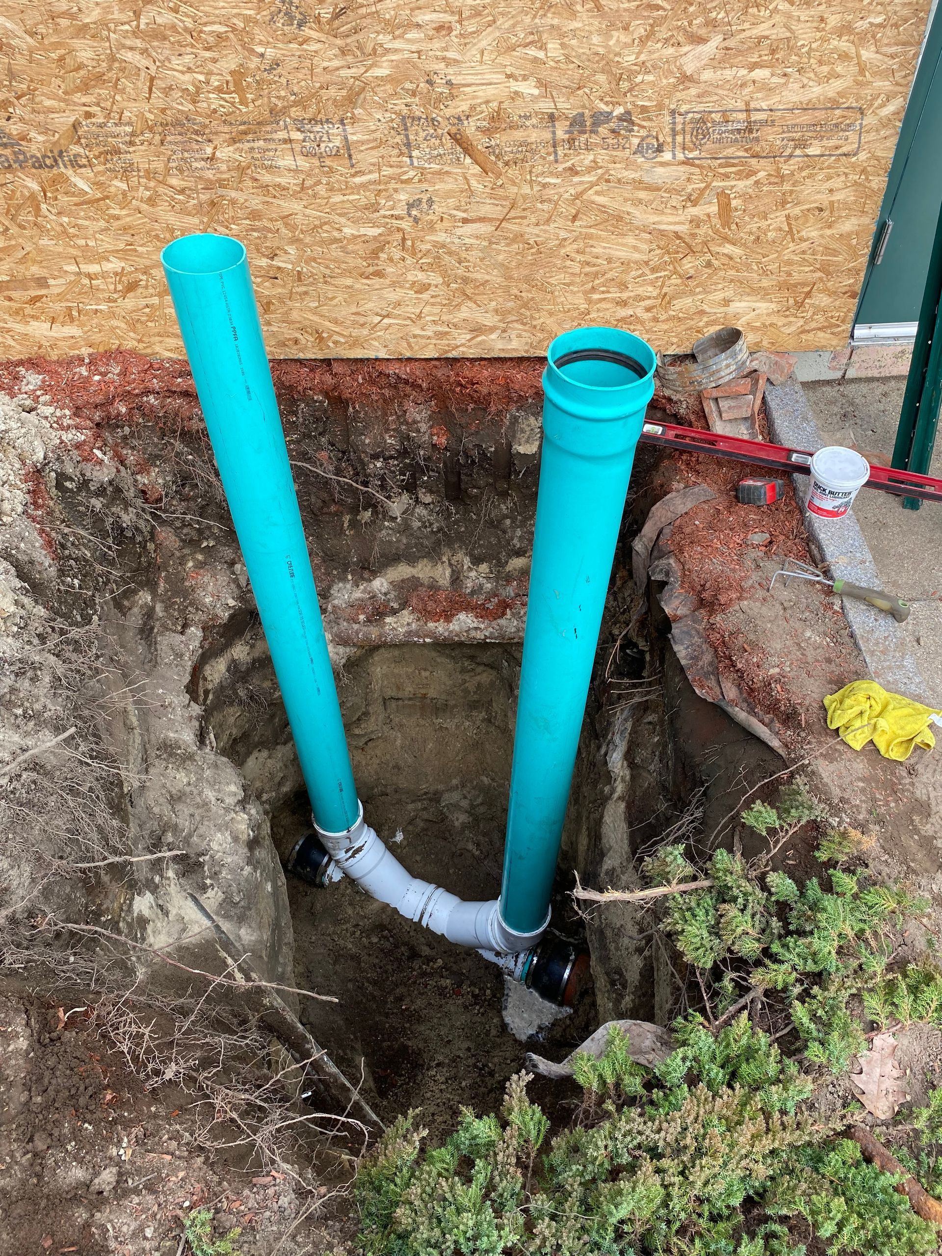 Two green pipes are being installed in a hole in the ground.