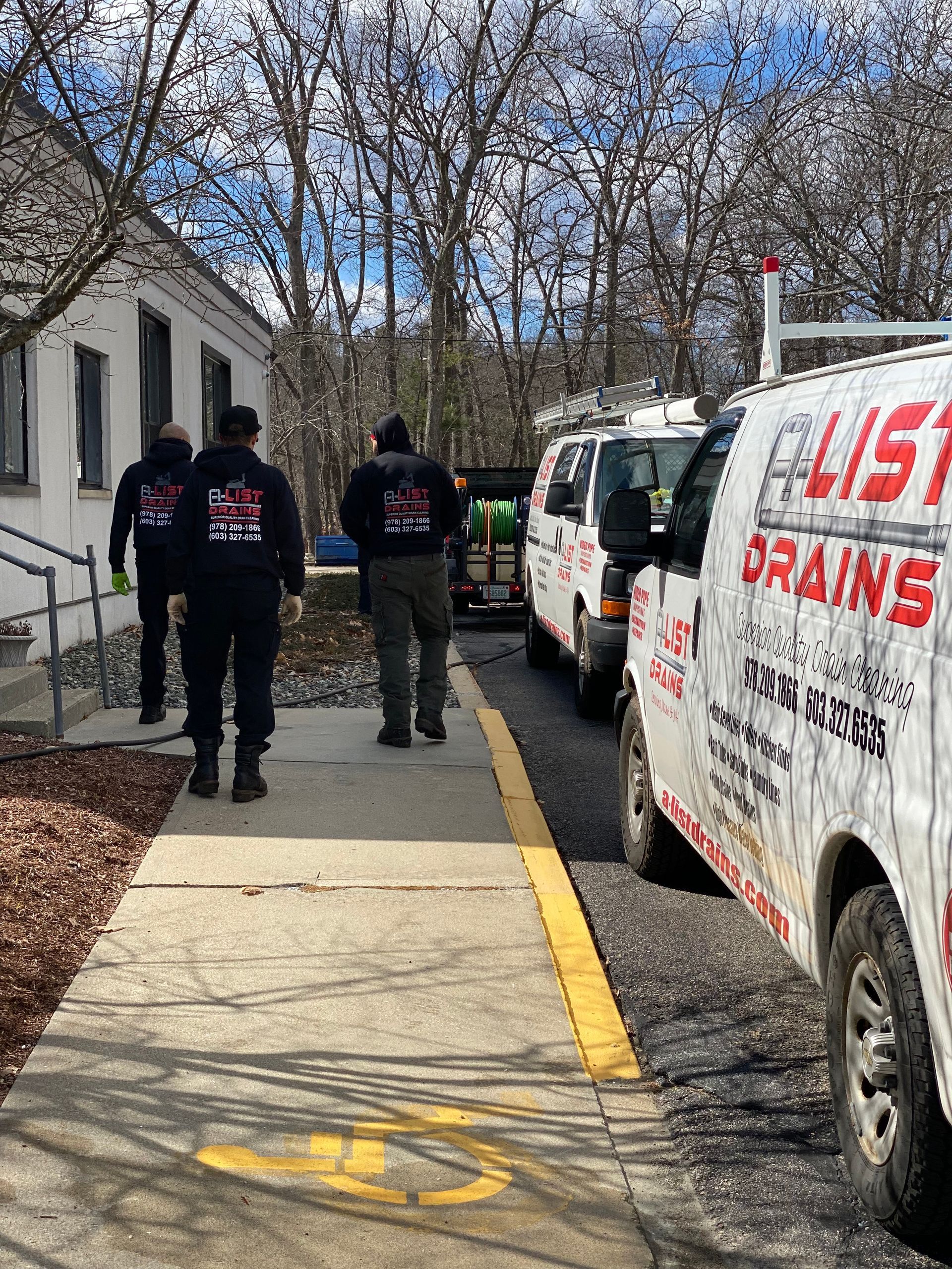 A group of men are walking down a sidewalk next to a row of vans.