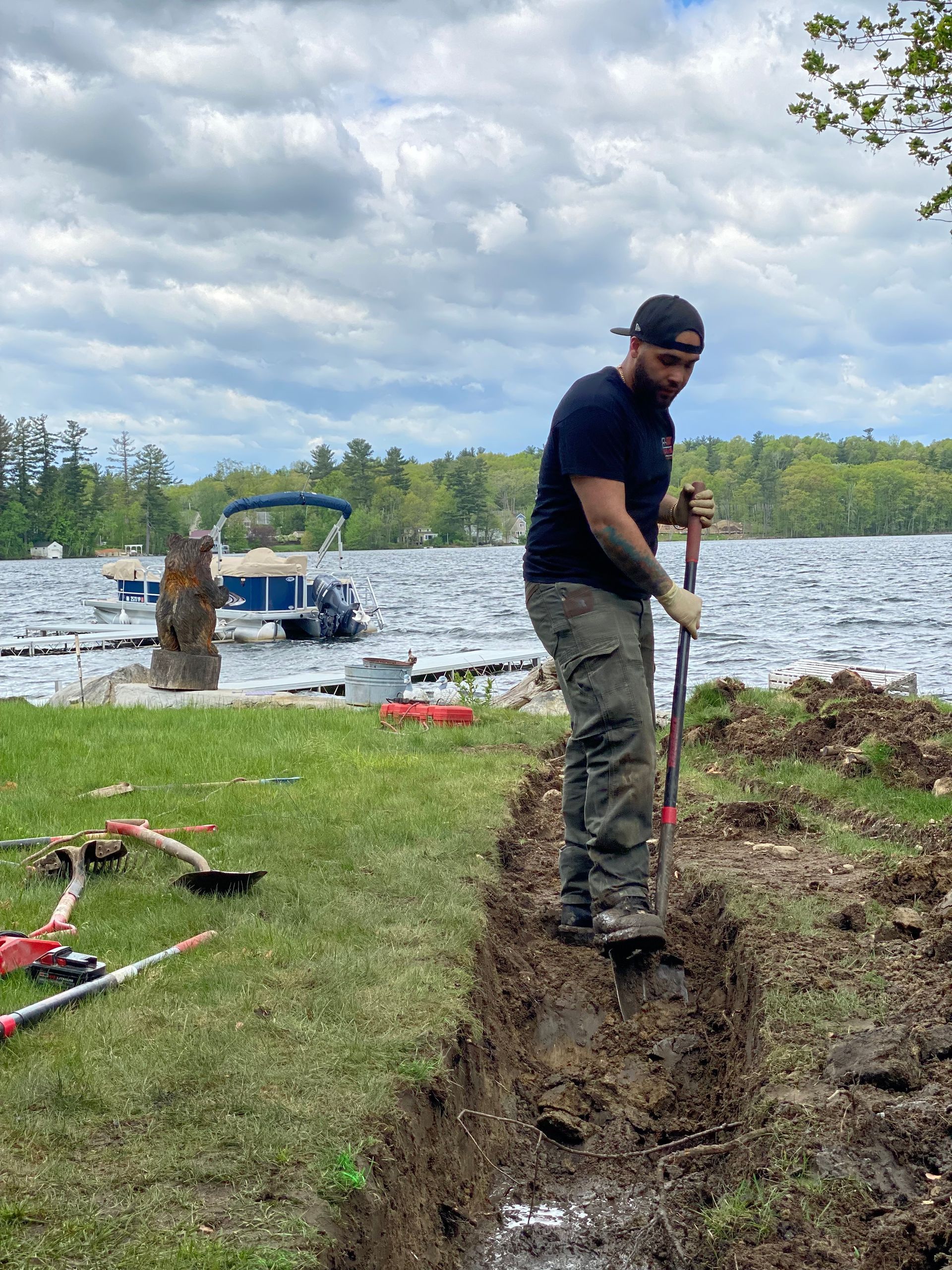 A man is digging in the dirt near a lake.