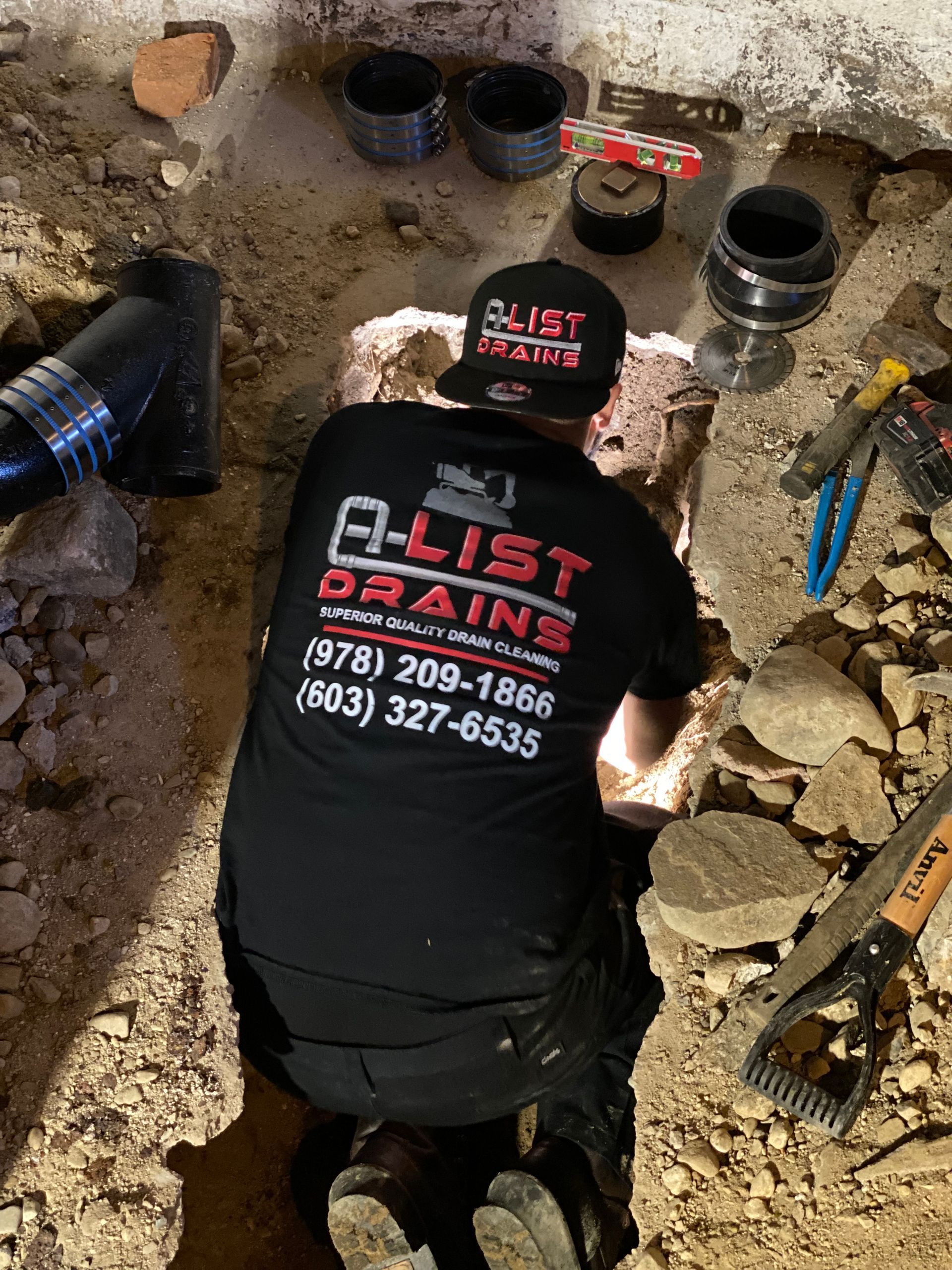 A man is working on a drain in a basement.
