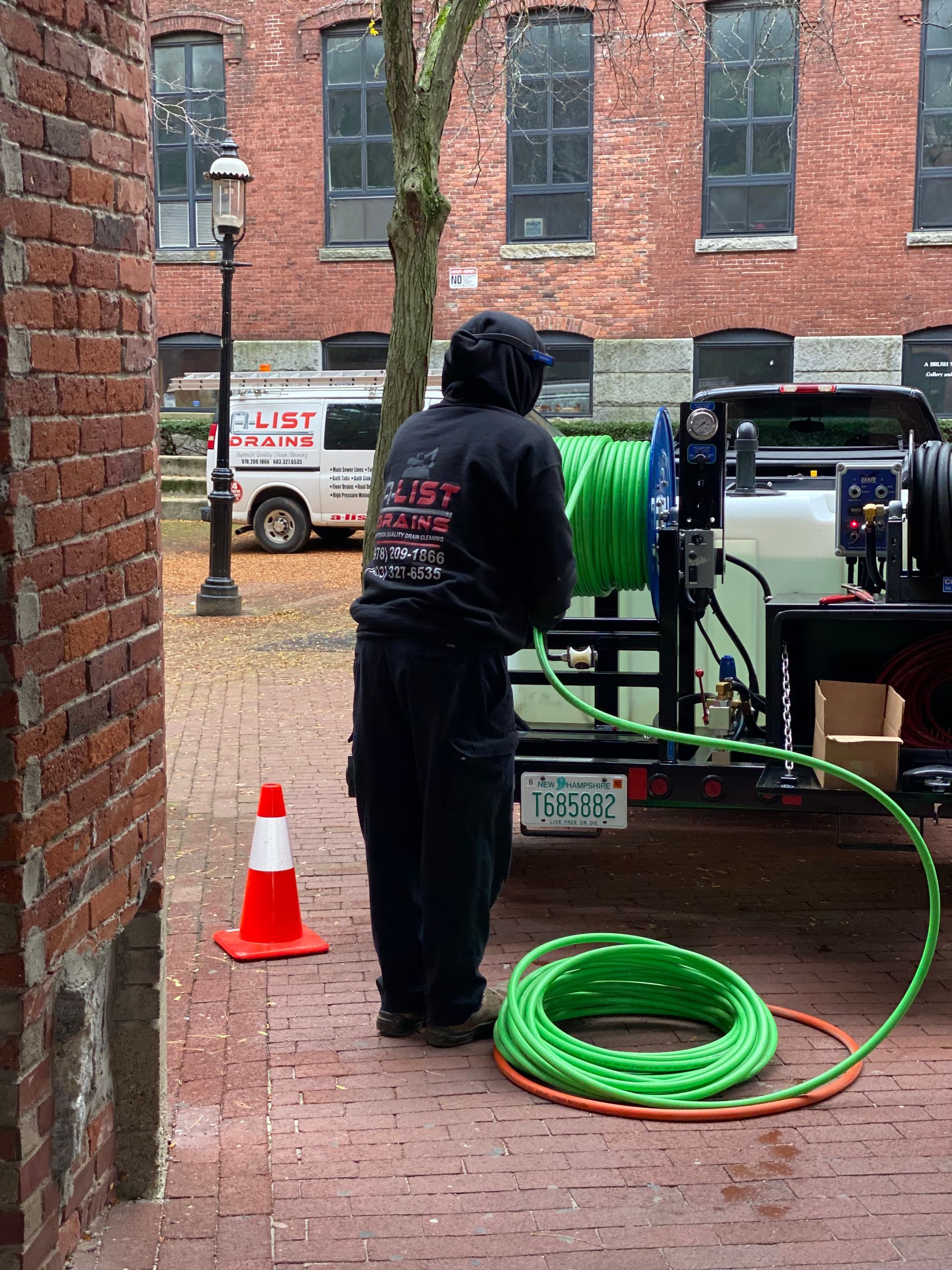 A man is standing in front of a truck with a green hose attached to it.