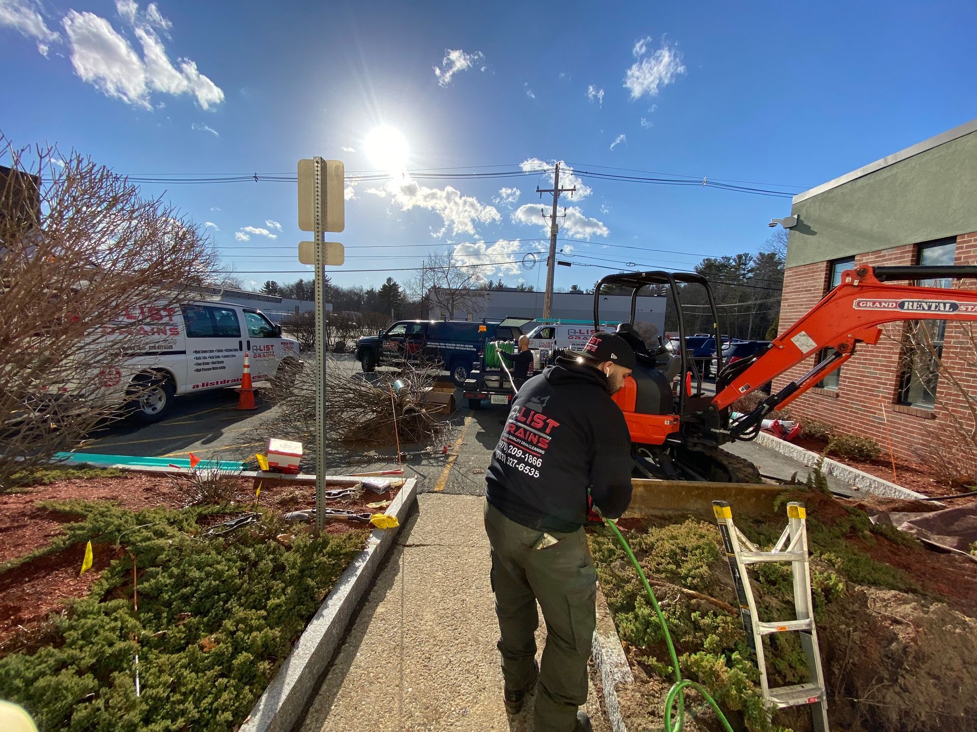 A man is walking down a sidewalk next to an excavator.