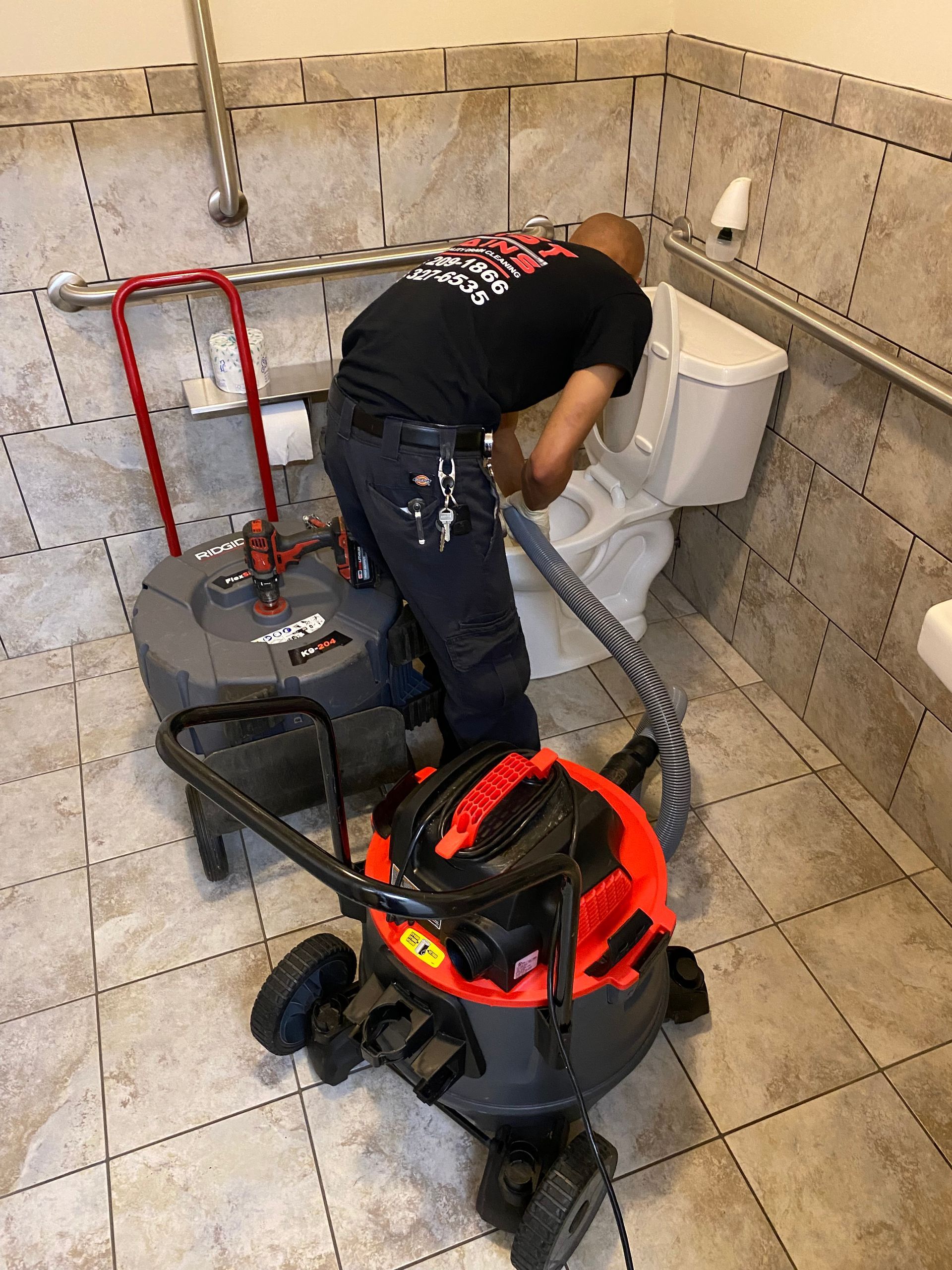 A man is cleaning a toilet with a vacuum cleaner.