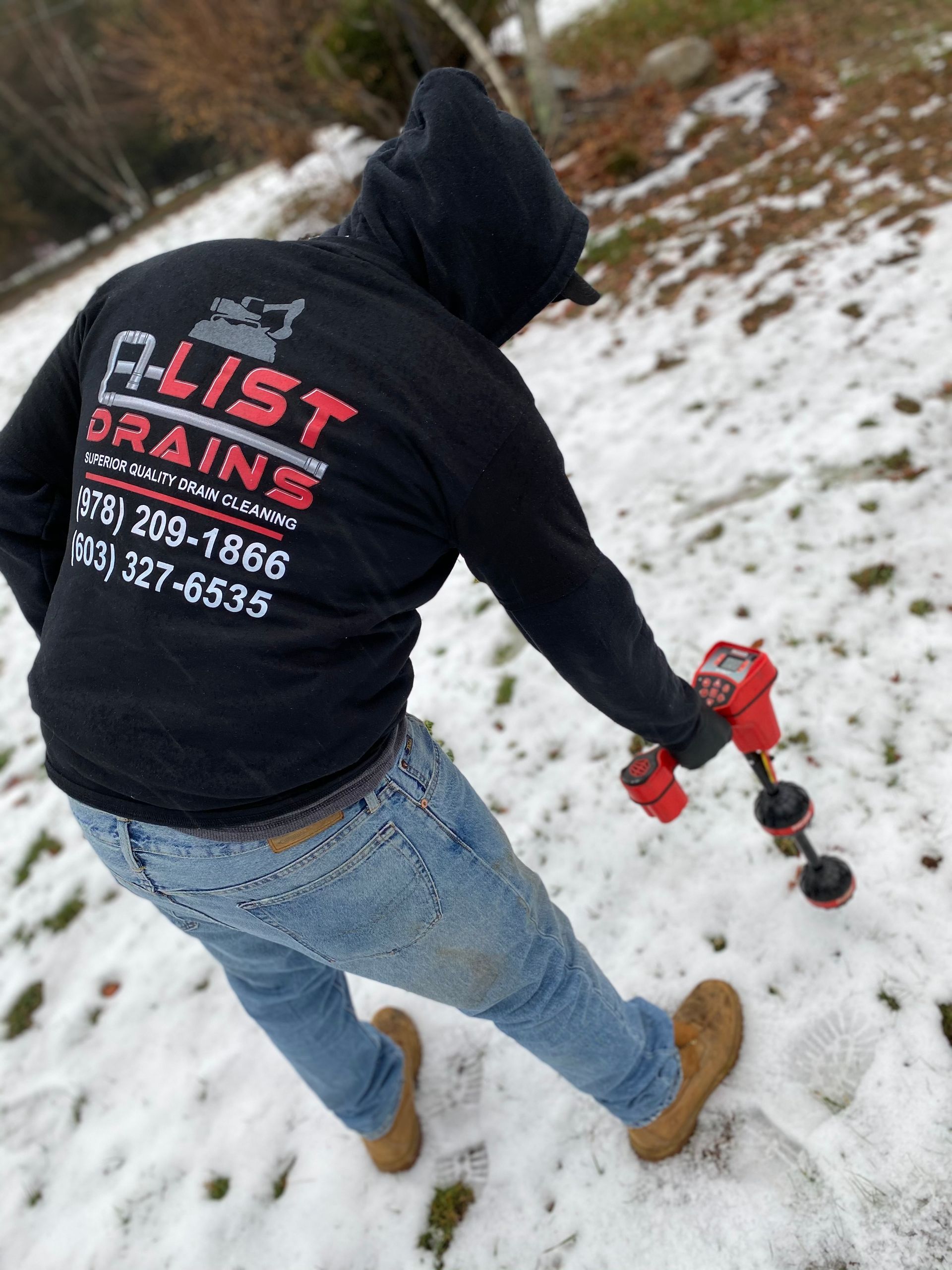 A man wearing a black a-list drains sweatshirt is standing in the snow